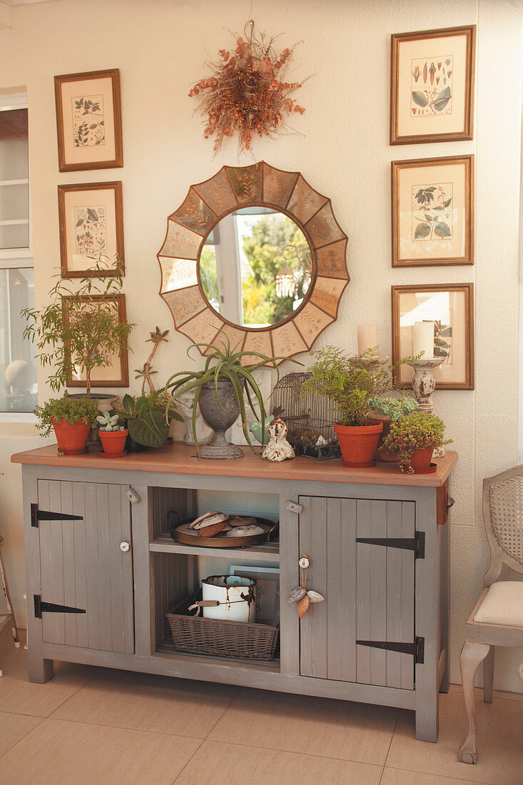 Bildergalerie und Spiegel überm grauen Sideboard im Landhausstil