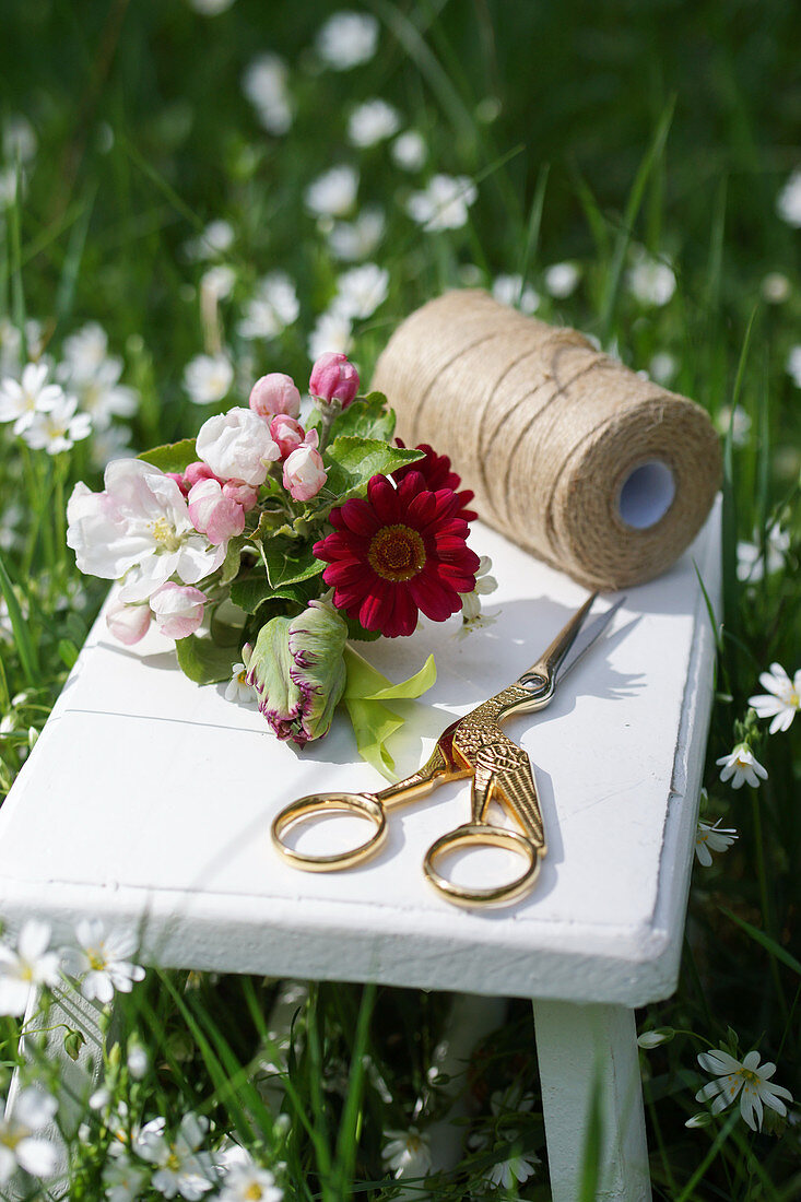 Small bouquet with apple blossoms, parrot tulips and red daisies on a side table in the meadow