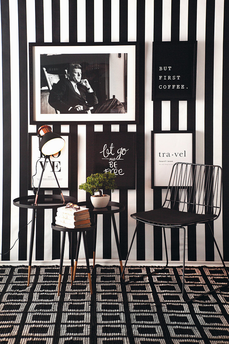 Chair and side table in black-and-white seating area with pictures on striped wallpaper