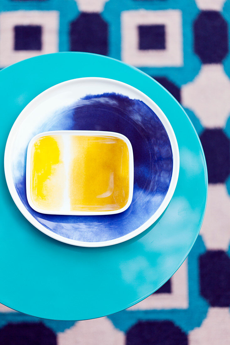 Yellow and blue bowls on round blue table (top view)