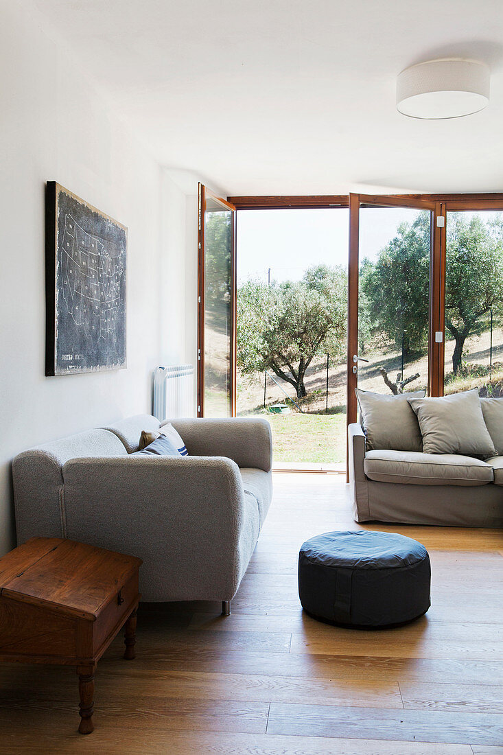 Grey sofas in living room and view of Tuscan countryside through open terrace doors