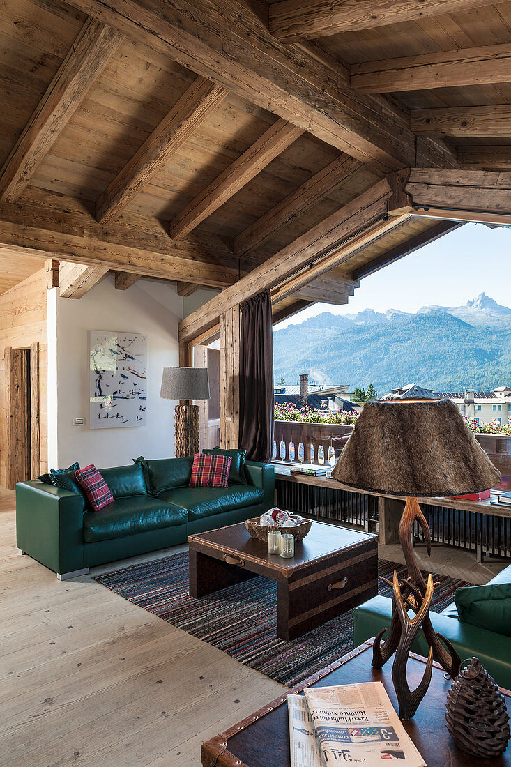 Grünes Ledersofa am Fenster im Wohnzimmer im rustikalen Holzhaus