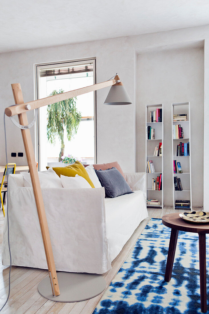 Sofa, swivelling standard lamp and blue and white rug in modern living room