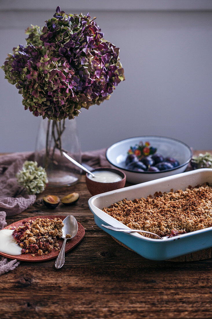 Plum crumble in a baking pan and served on a ceramic plate