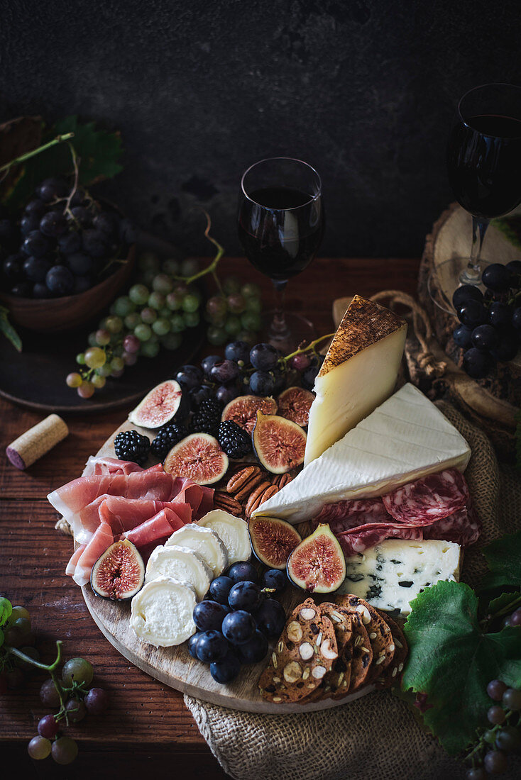 Käseplatte serviert mit Früchten, Nüssen und Rotwein
