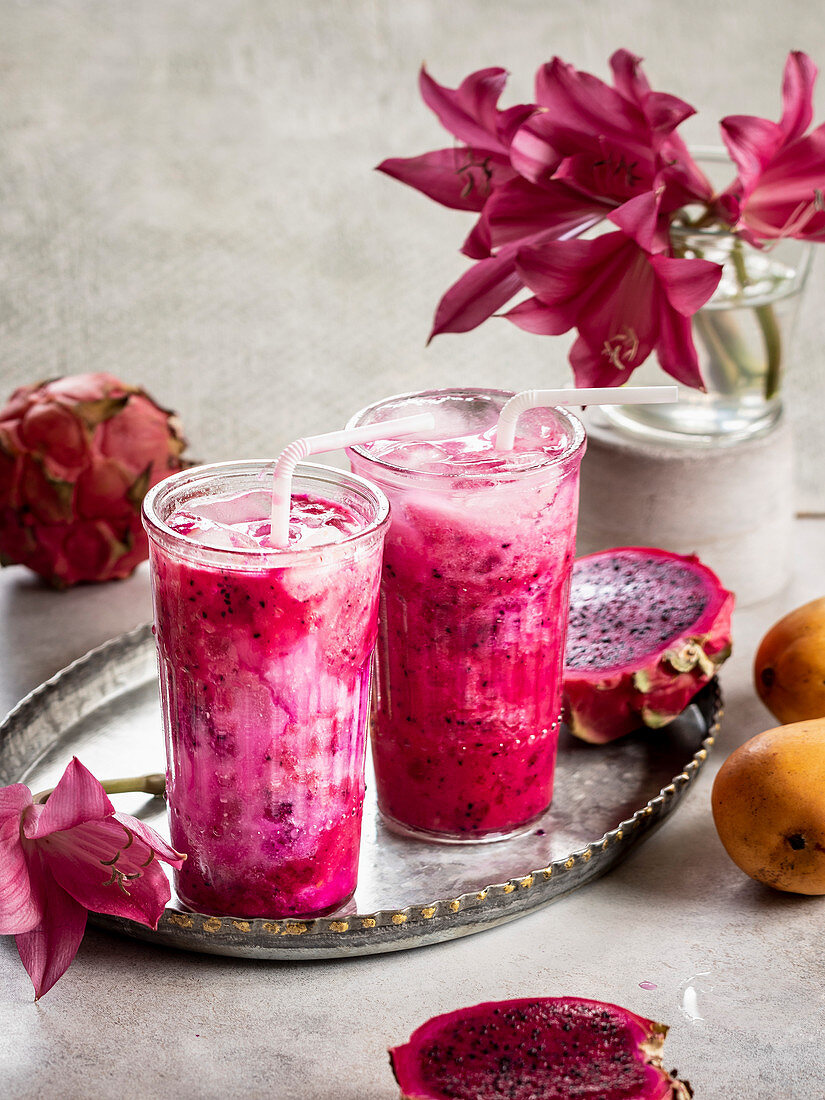 Pitahaya-Smoothie mit Mango und Kokosmilch in Gläsern auf Tablett