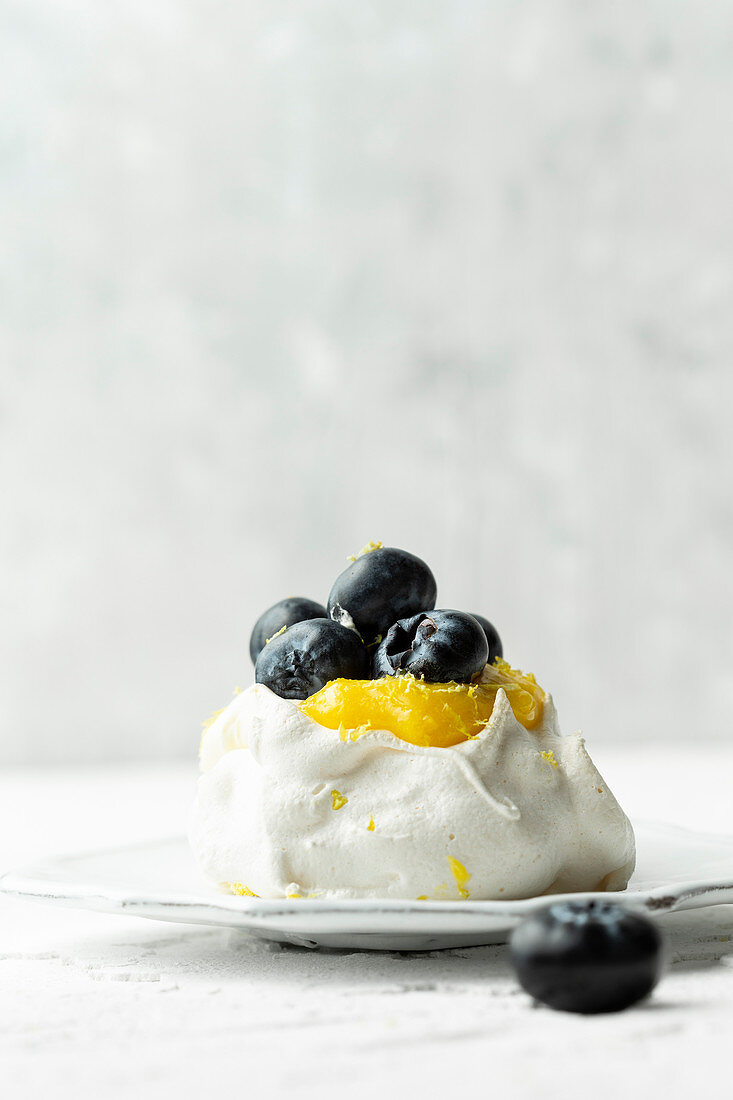Mini-Pavlova mit Lemon Curd und Blaubeeren vor weißem Hintergrund
