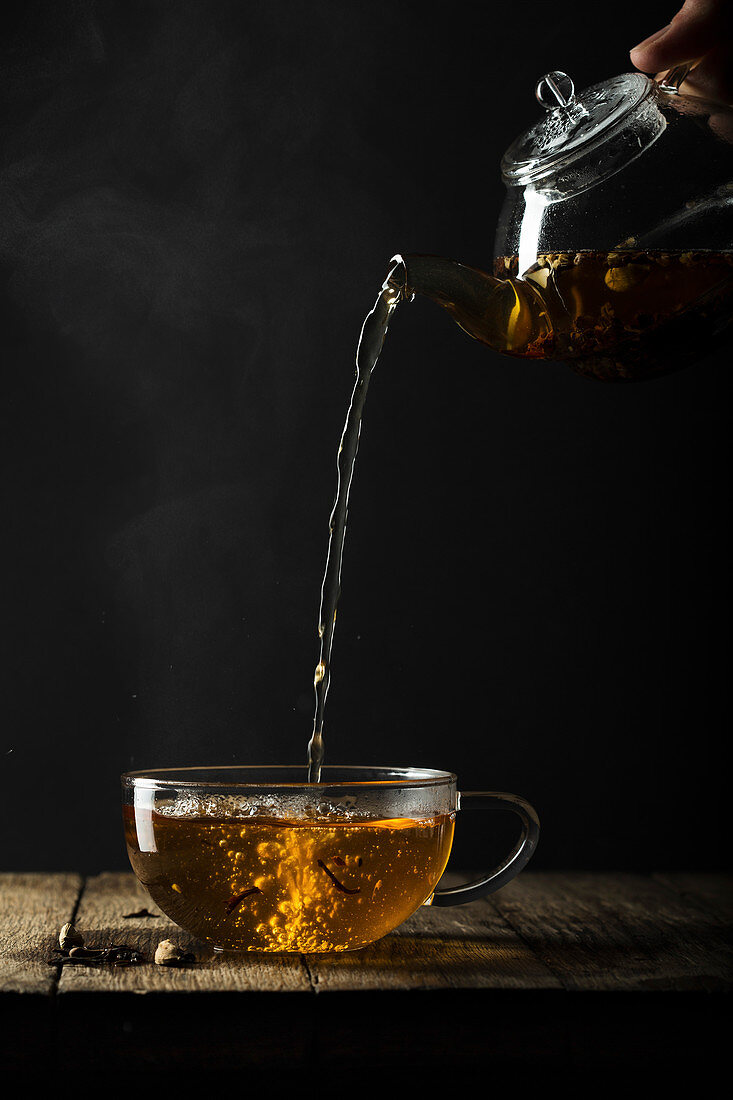 Tee wird aus Glaskanne in Teetasse gegossen