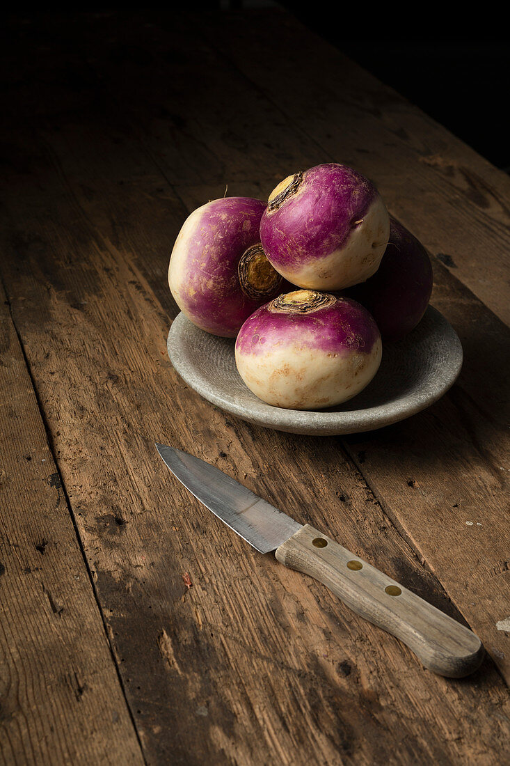 Raw turnips in a bowl on a rustic wooden surface