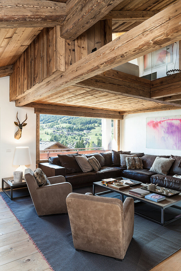 Velvet armchairs and leather sofa in living room of wooden house