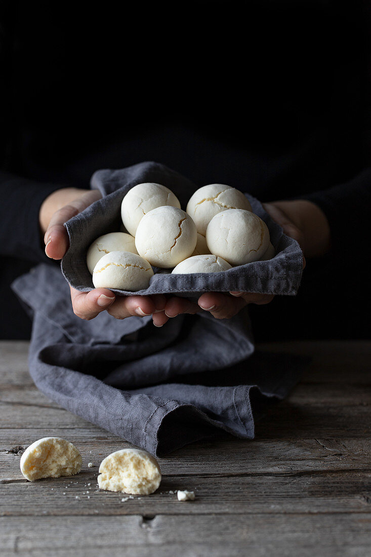 Anonymous female holding handful of delicious cornstarch cookies in cloth napkin over lumber table