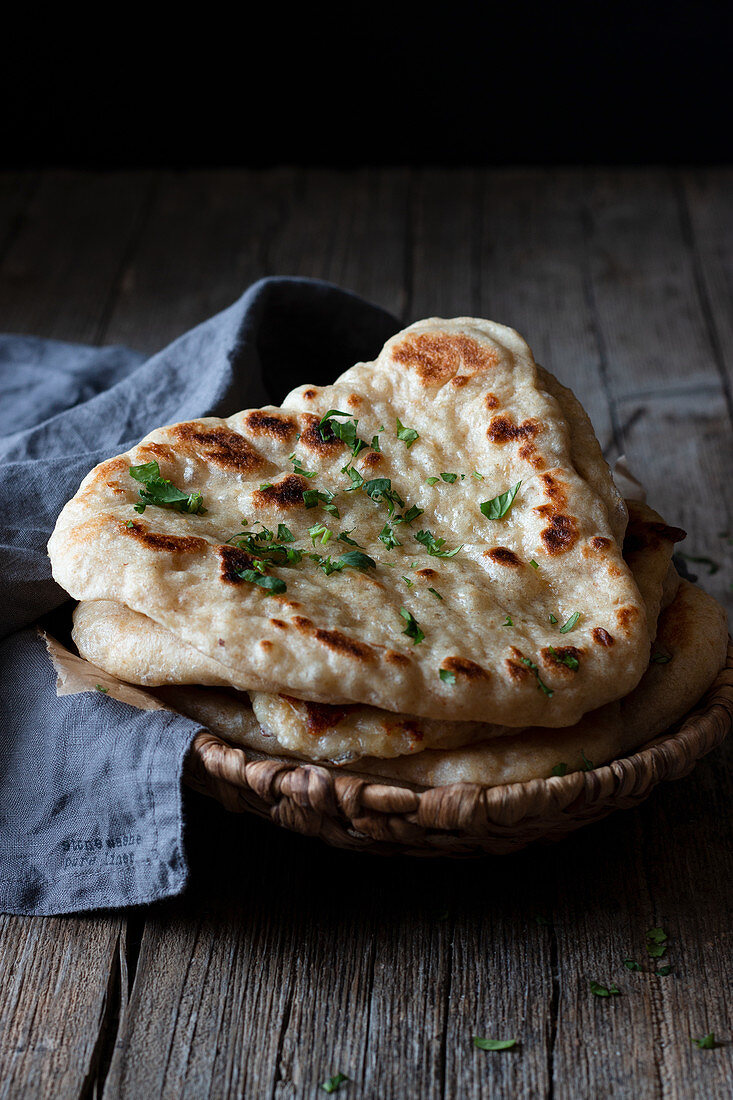 Plate with delicious naan bread and cloth napkin placed on weathered lumber table