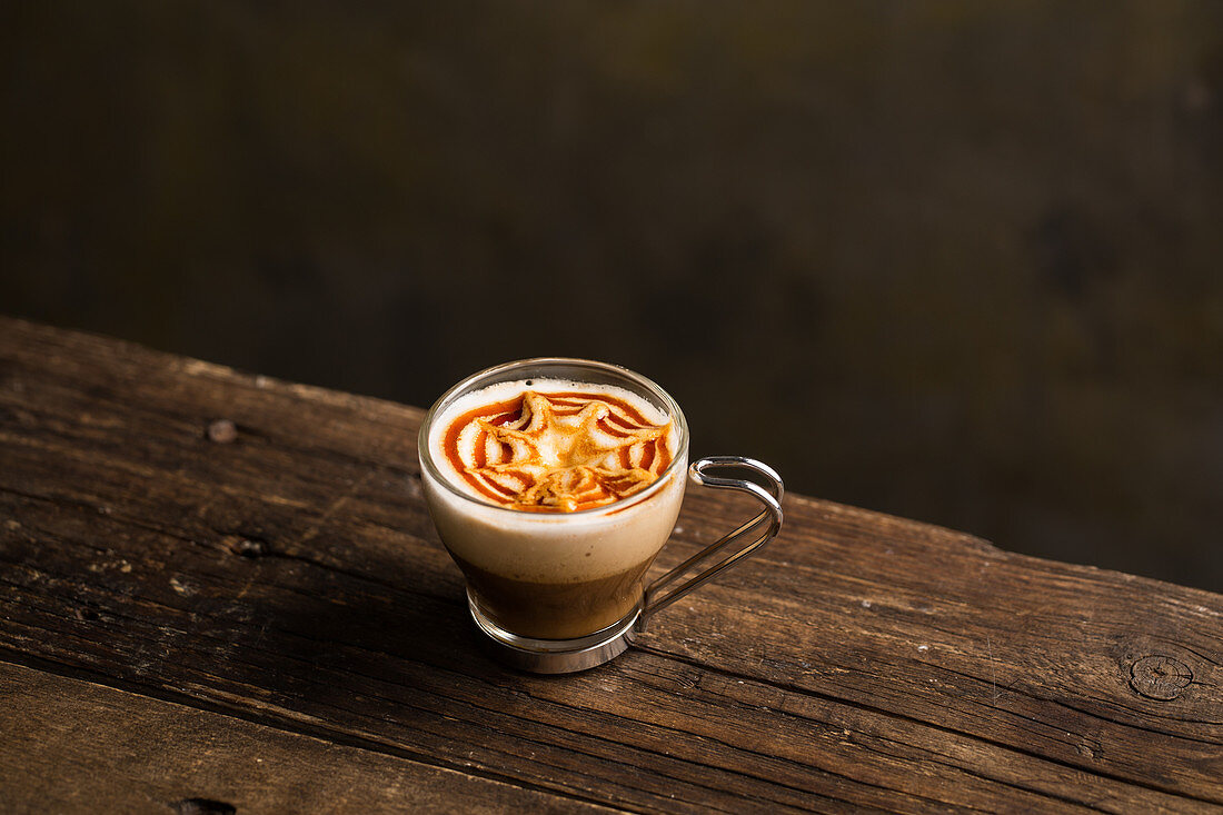 From above delicious fragrant brown beverage with white foam in glass cup on wooden table