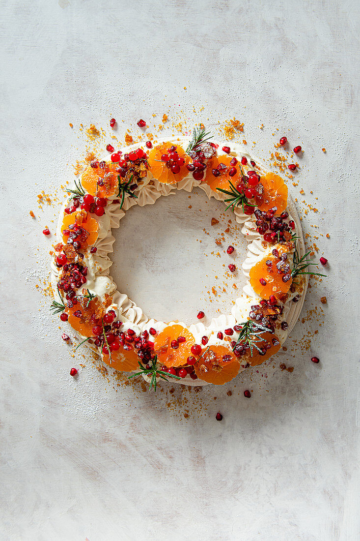 Meringue wreath with whipped cream, pomegranate, satsumas, redcurrants and praline