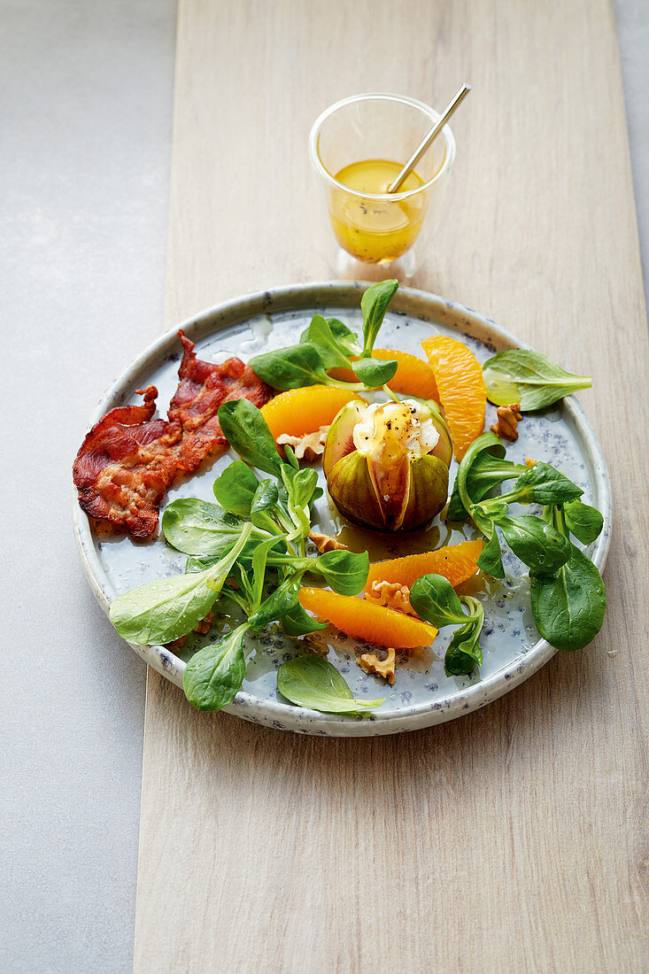 Gratinated figs with goat's cheese, bacon, orange fillets and lamb's lettuce