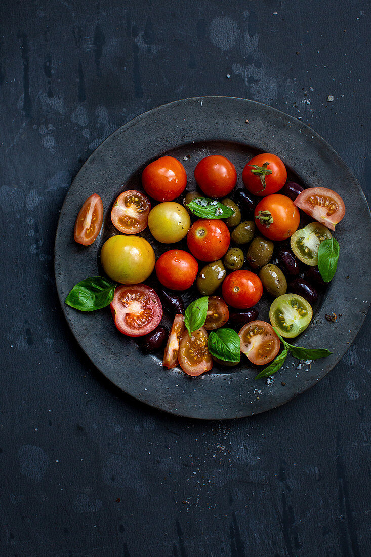 A tomato salad with olives and basil