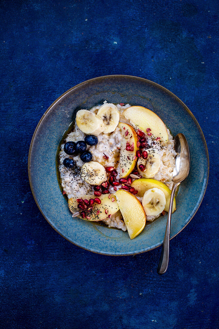 Porridge with fresh fruit on a blue plate on a blue surface