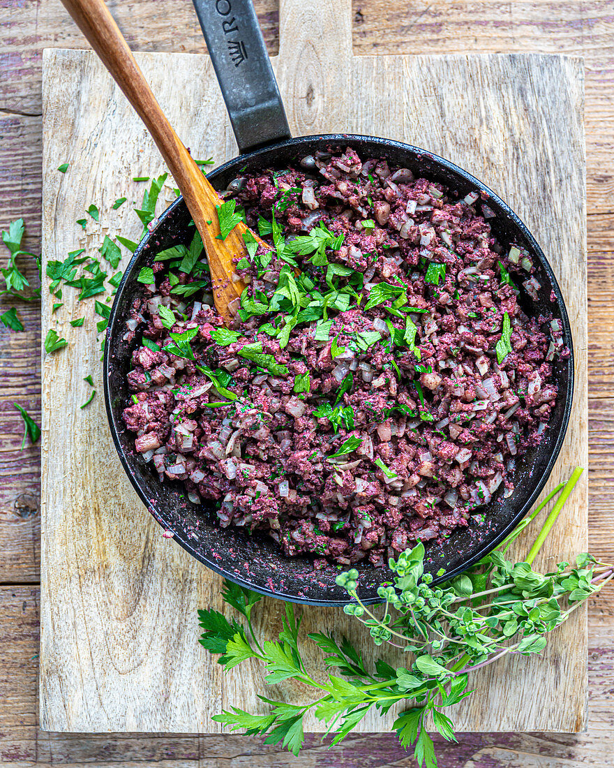 Chopped creamy sausage with herbs in a pan