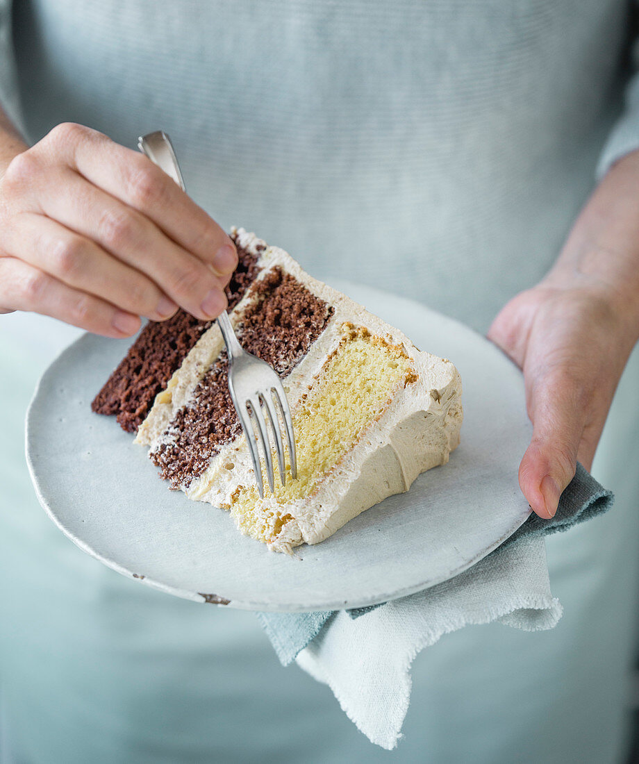 Person isst ein Stück Schokoladen-Schichttorte mit Dirty Chai Creme