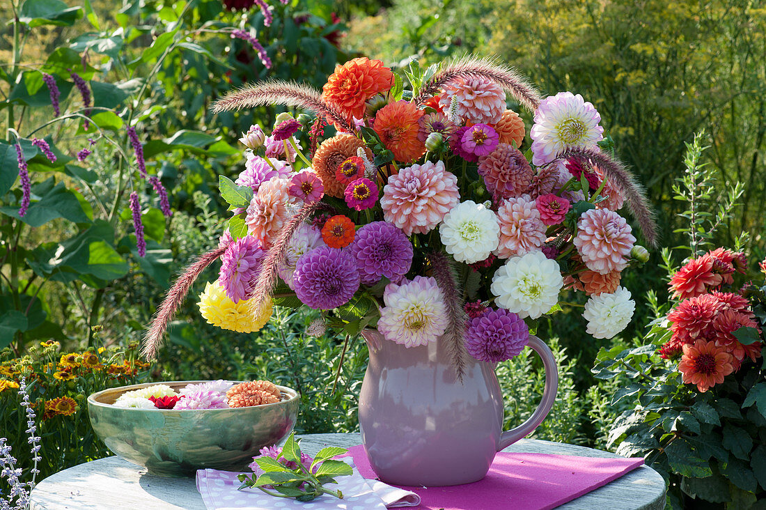 Bouquet of dahlias, zinnias and fountain grass, bowl with flowers in the water