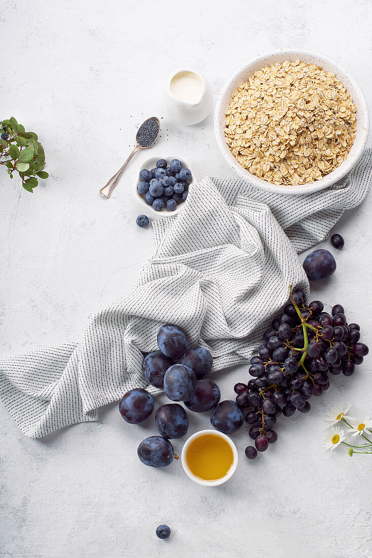 Zutaten für gesundes Frühstück: Haferflocken, Pflaumen und Trauben