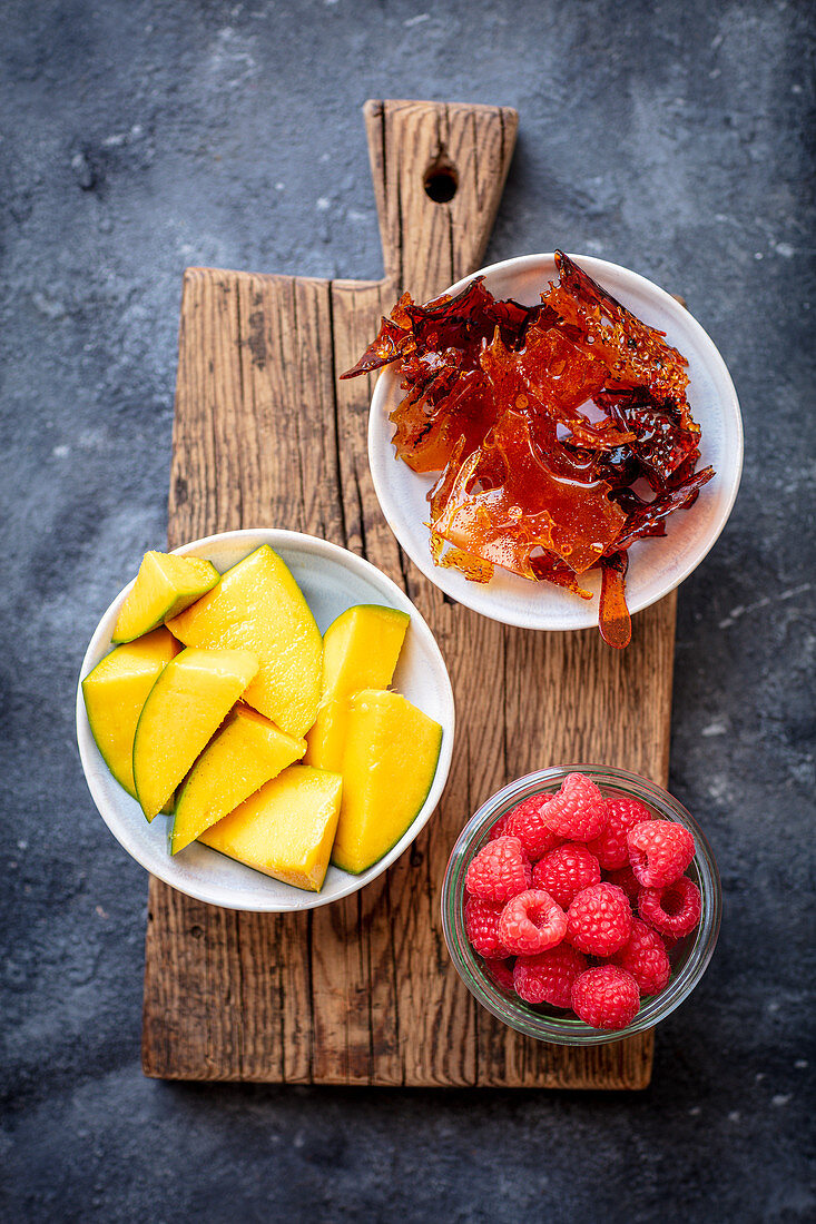 Mango, Himbeeren und Karamell auf Schneidebrett