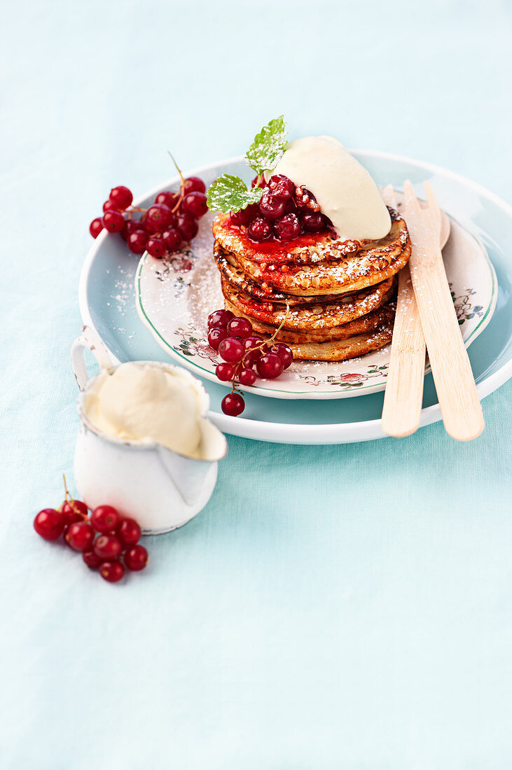 Pancakes mit Sahne, Puderzucker und roten Johannisbeeren