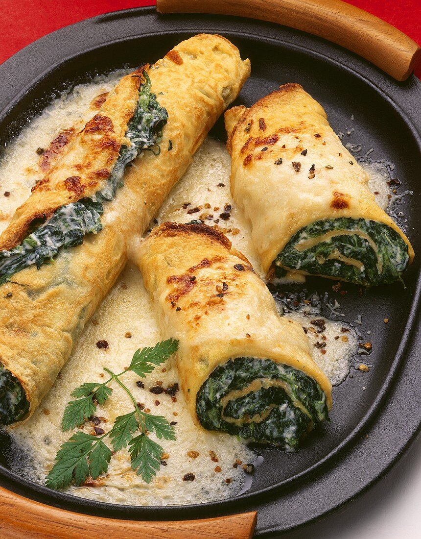 Gratin of pancake rolls with cream and spinach filling