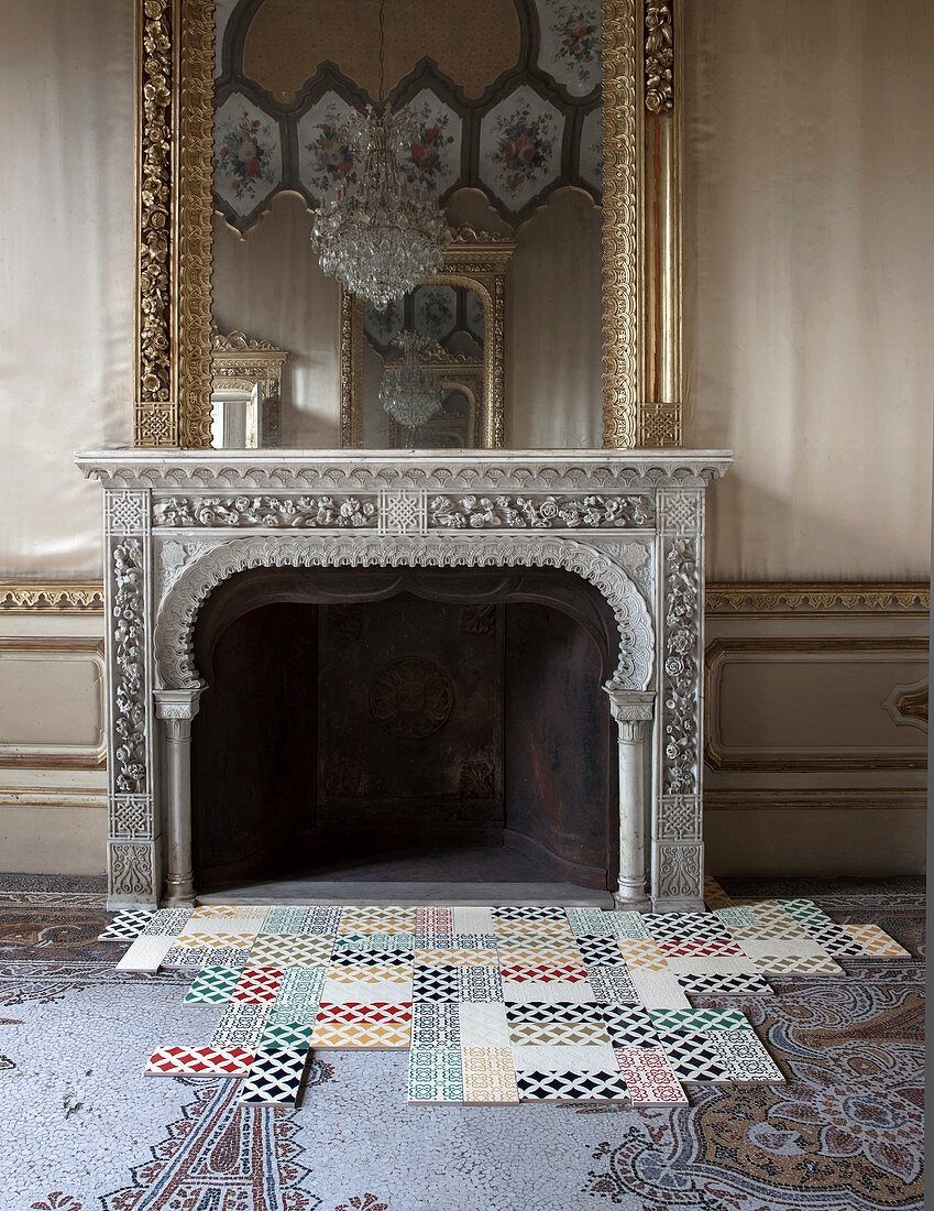 Moderne Fliesen mit geometrischen Mustern auf antikem Mosaikfliesenboden vor Kamin