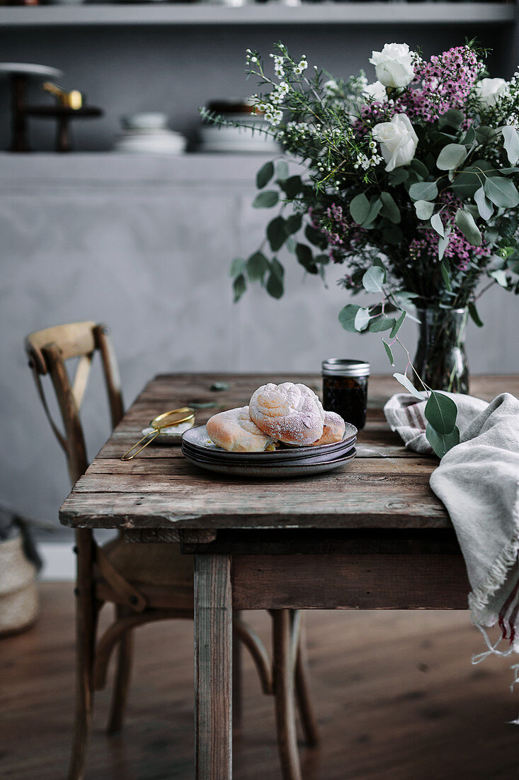 Blumenstrauß und Gebäck auf rustikalem Holztisch in Landhausküche