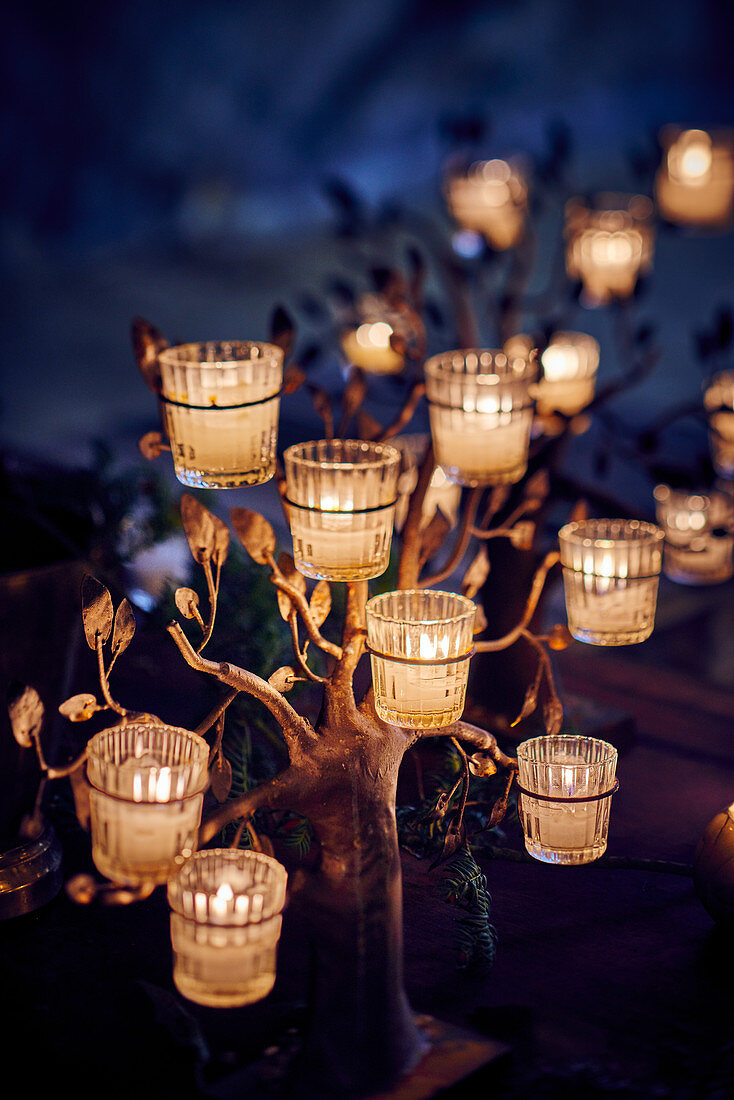 Glass tealight holders on tree-shaped frame decorating table