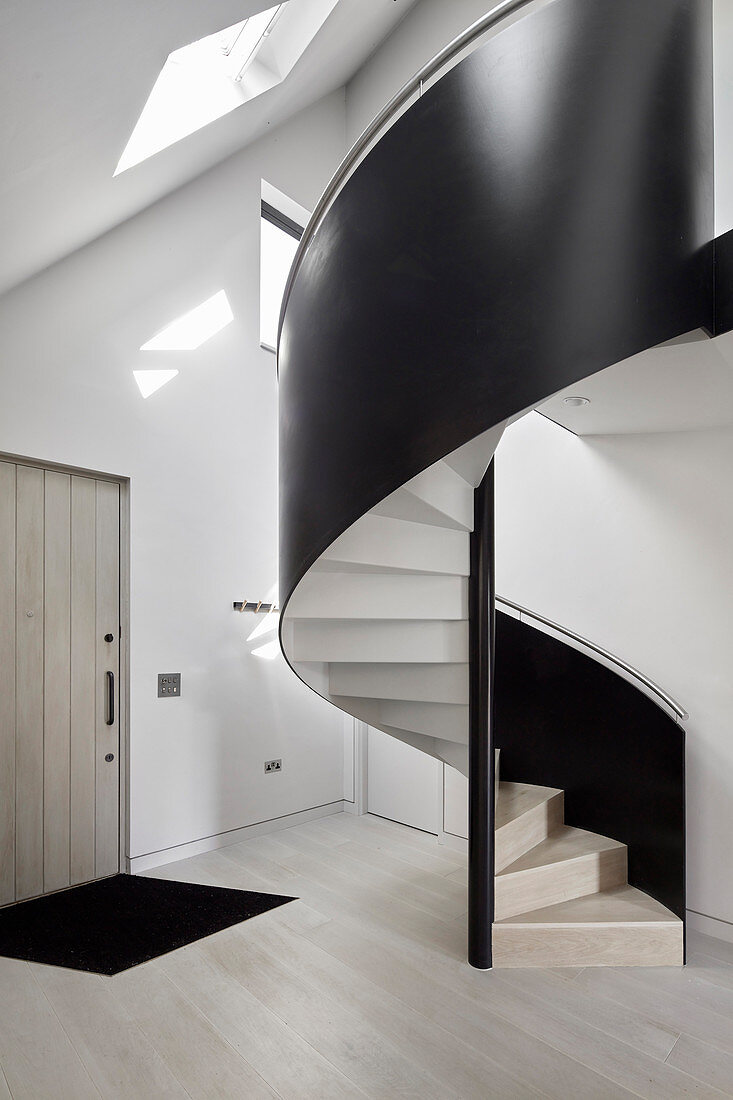 Black, modern spiral staircase in foyer of architect-designed house