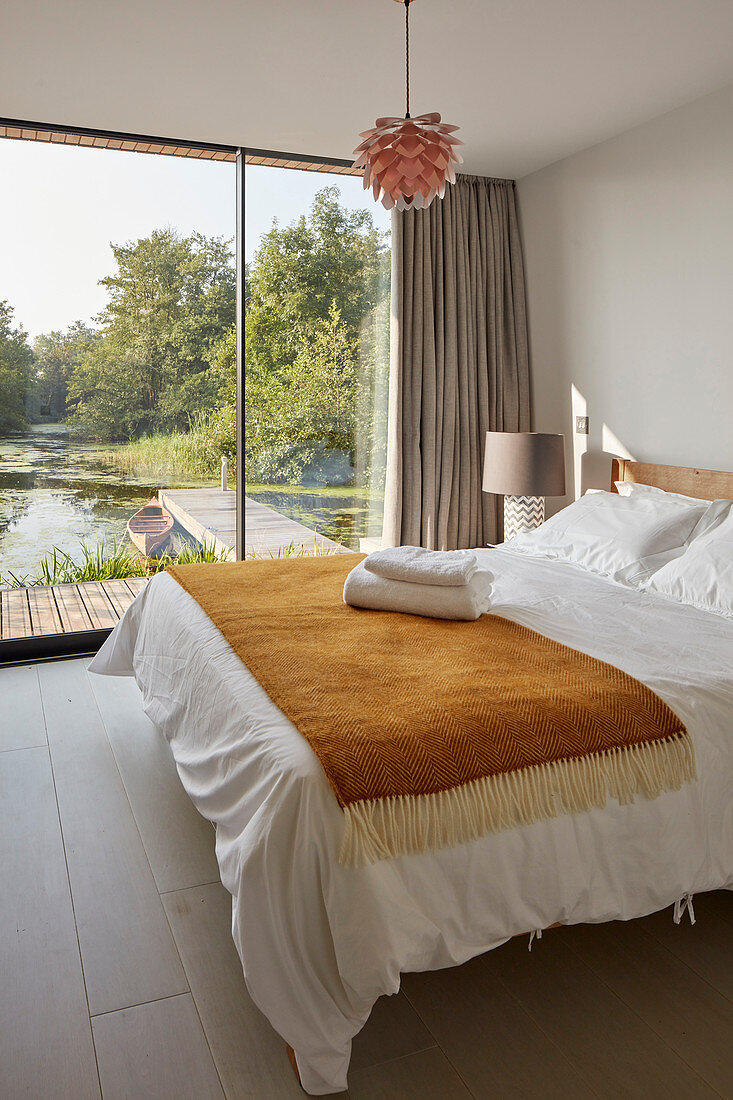 Bedroom with glass wall overlooking lake jetty