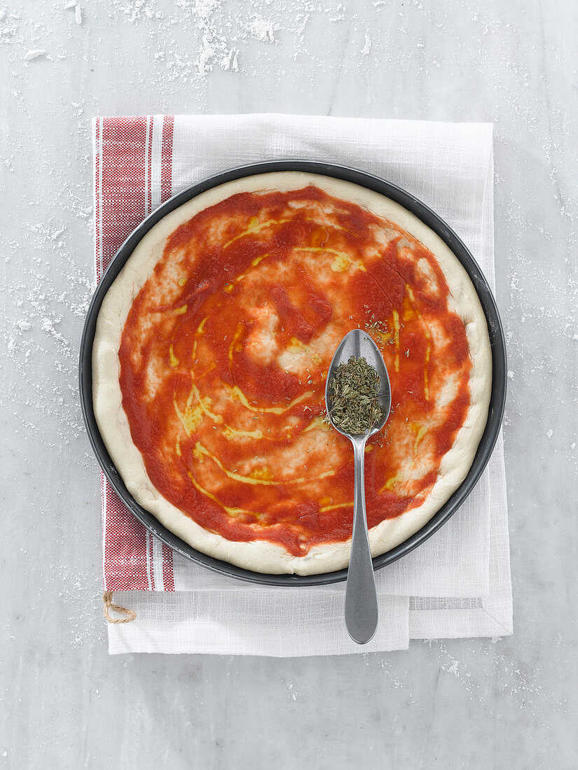 Pizzateig mit Tomatensauce, Olivenöl und Oregano