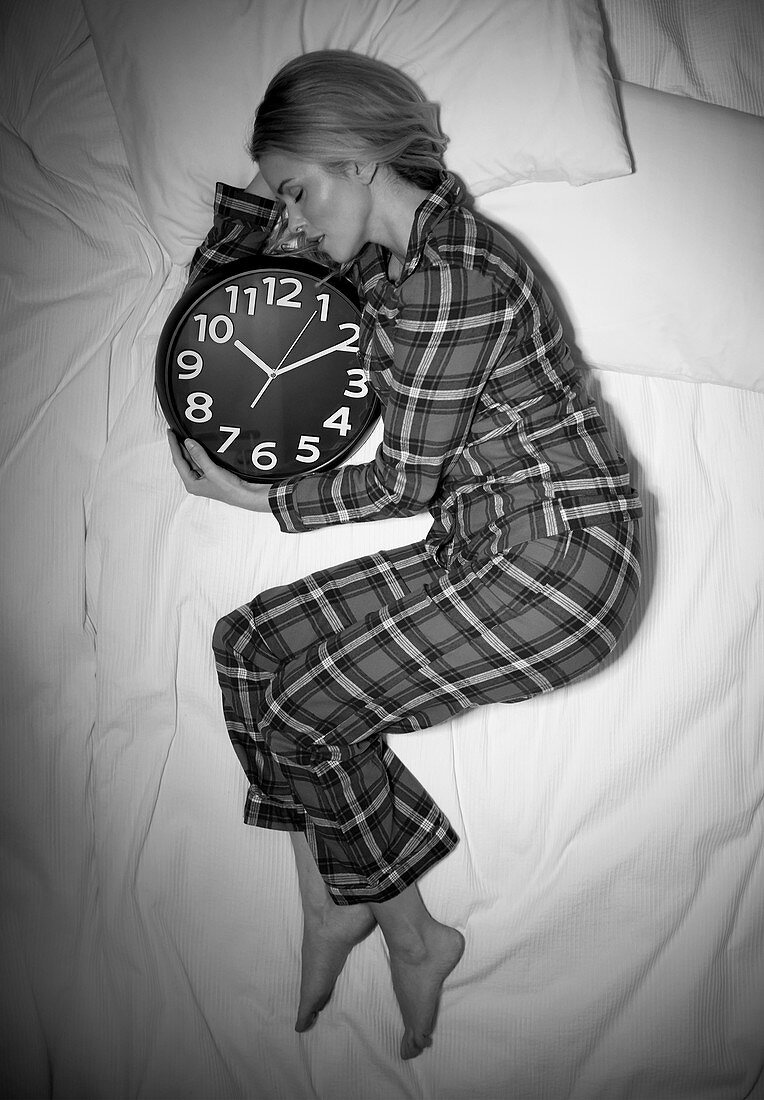 Woman sleeping in bed with clock
