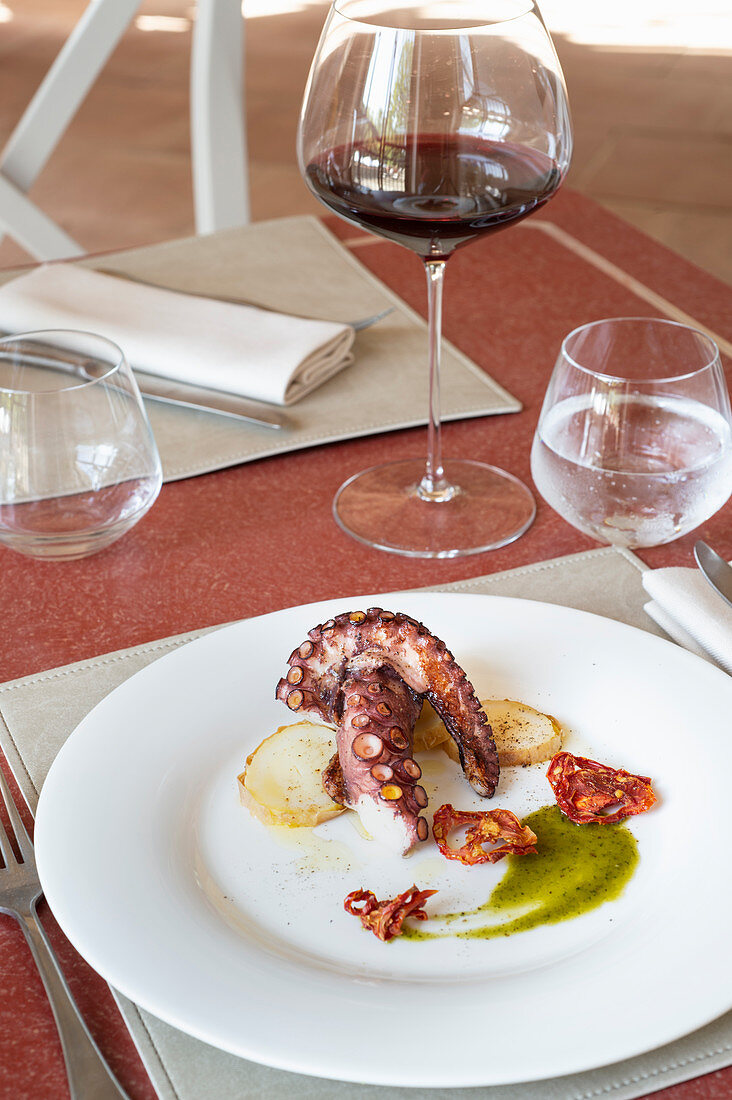 Restaurant dish with octopus, potatoes and sliced dried tomatoes