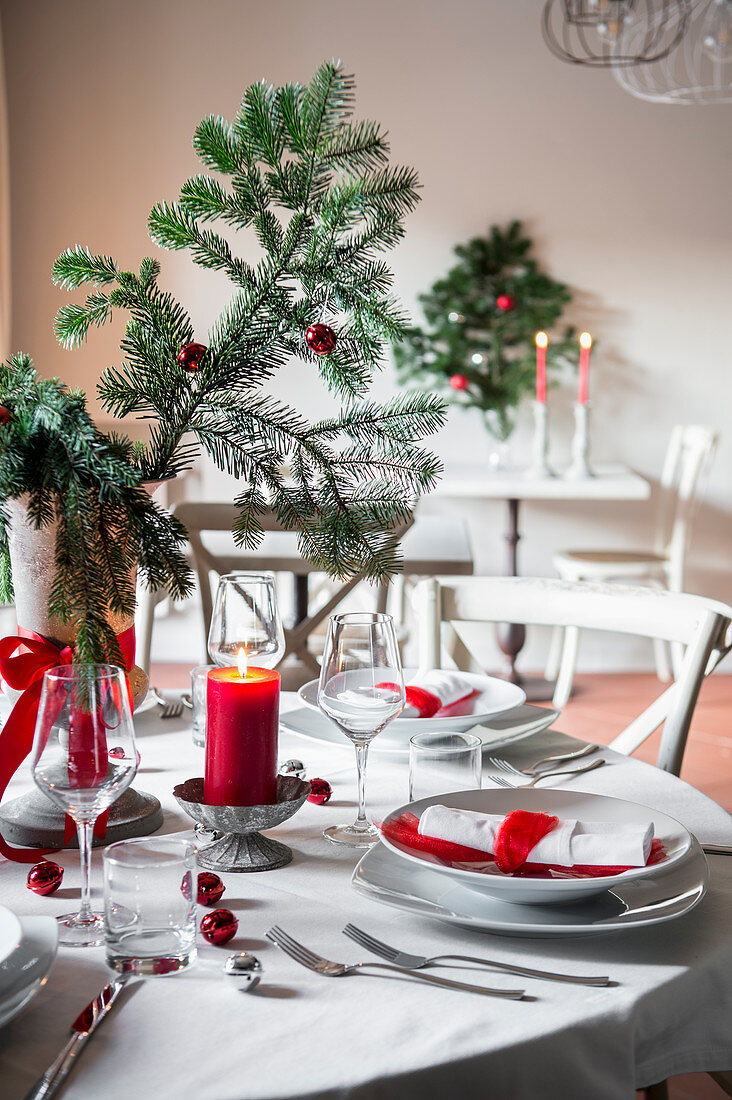 Christmas table setting with red and white decor and fir branches