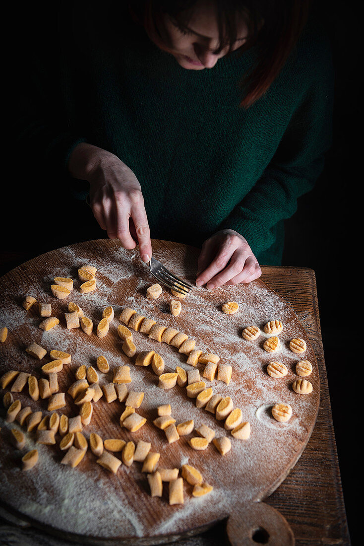 Making pumpkin gnocchi: flatten the pieces of dough with a fork