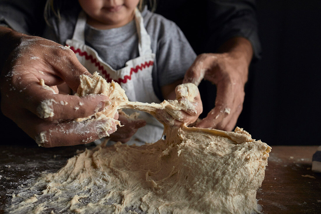 Father and daughter kneading the dough together