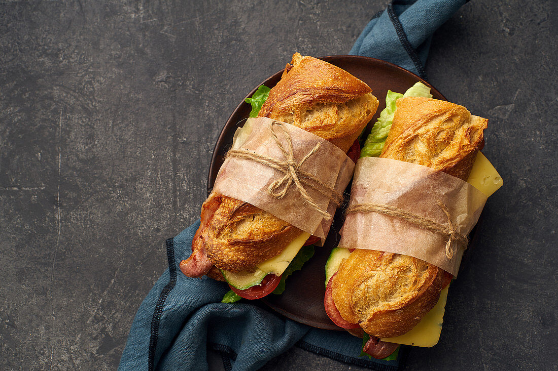 Baguette sandwich with bacon, chedder cheese, mustard, lettuce and vegetables