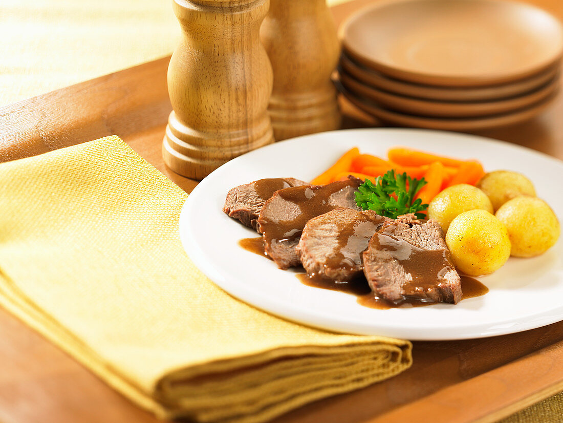 Sliced roast beef potato carrot on wooden tray