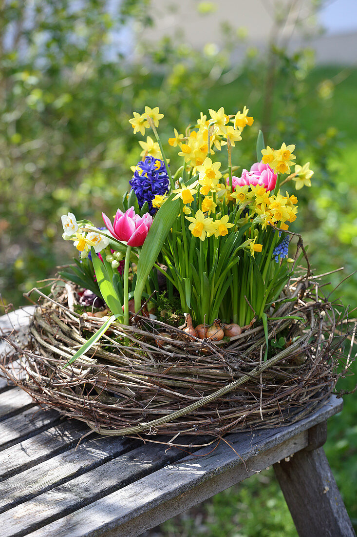 Kranz aus Zweigen mit bunten Frühlingsblumen in der Mitte