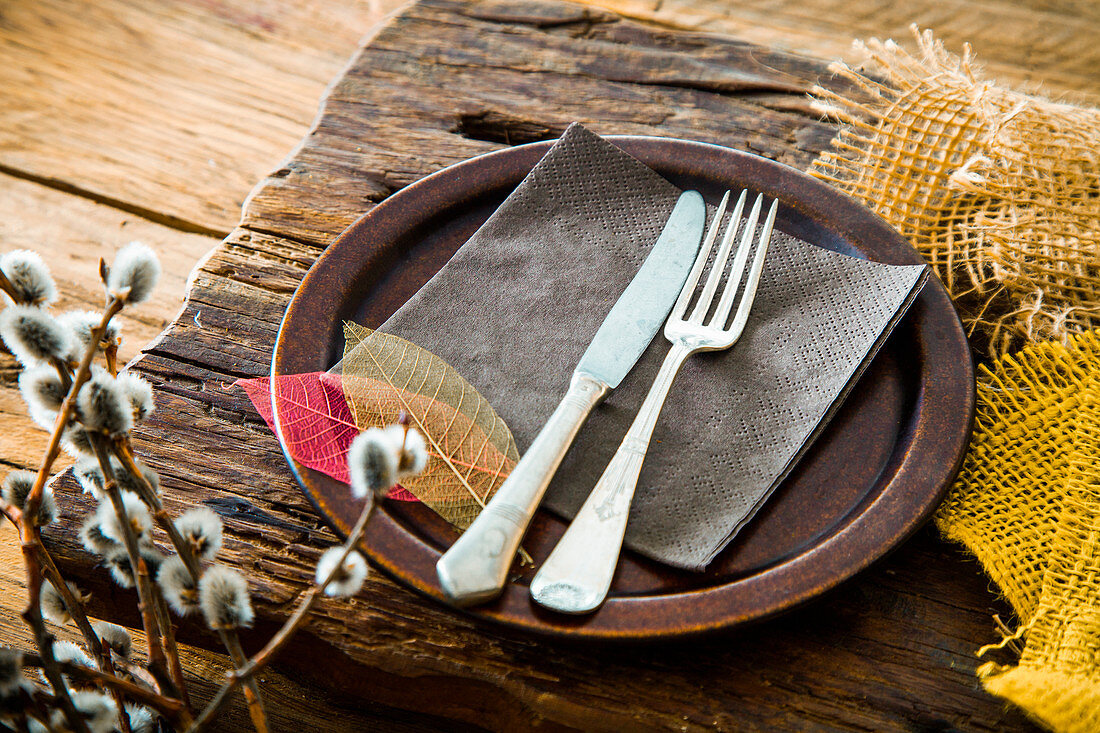A rustic spring place setting decorated with leaves and catkins