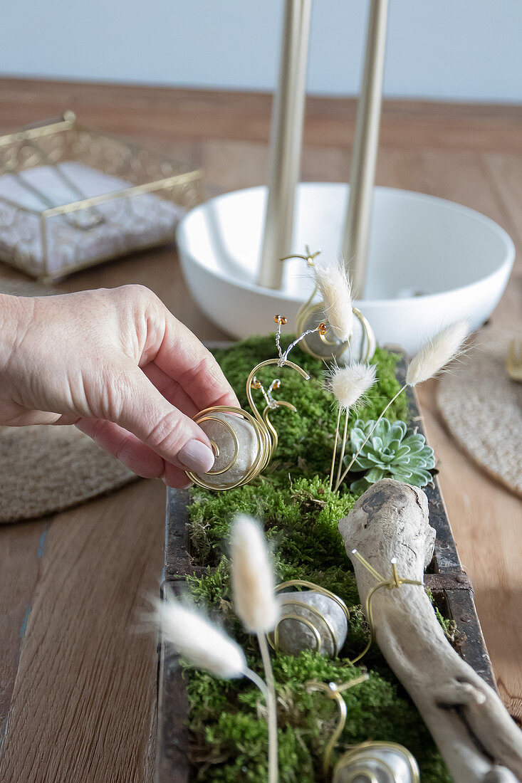 Selbstgemachte Tischdeko mit Schnecken aus Steinen und Draht