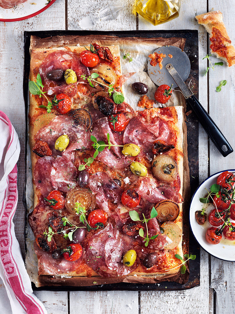 Pizza mit Salami, Tomaten, Oliven, Oregano und Zwiebeln
