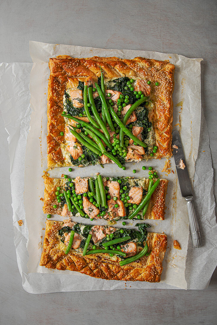 Puff pastry salmon tart with dill cream cheese, spinach, beans and peas
