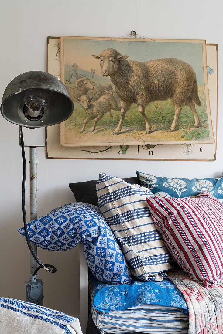 Old poster of sheep above bench with blue-patterned cushions