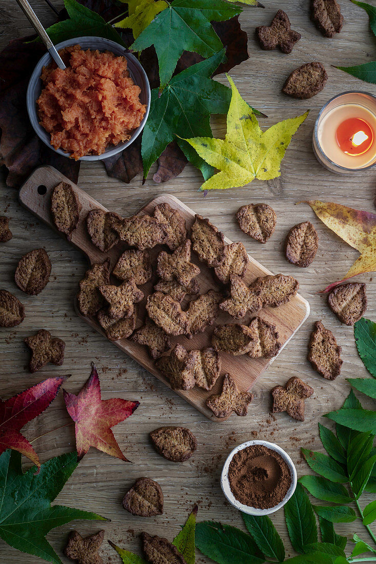 Tasty biscuits and autumn leaves placed on wooden table