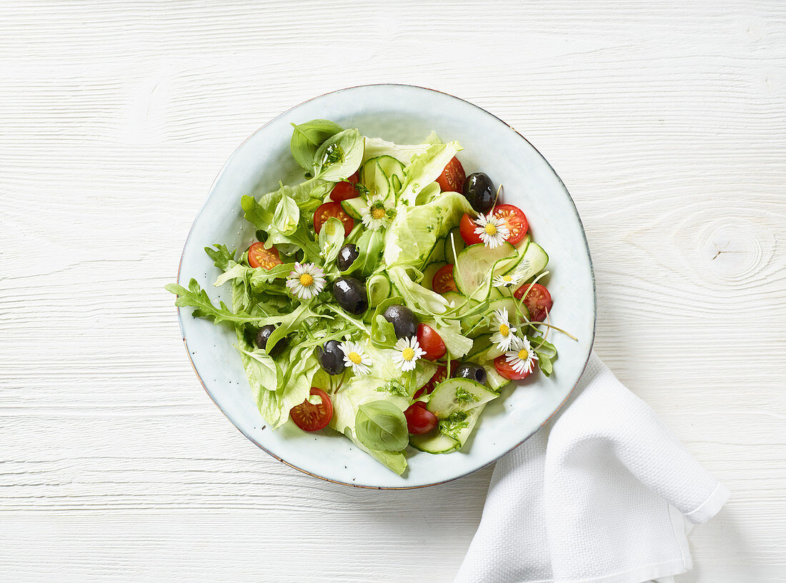 Bunter Sommersalat mit schwarzen Oliven und Gänseblümchen