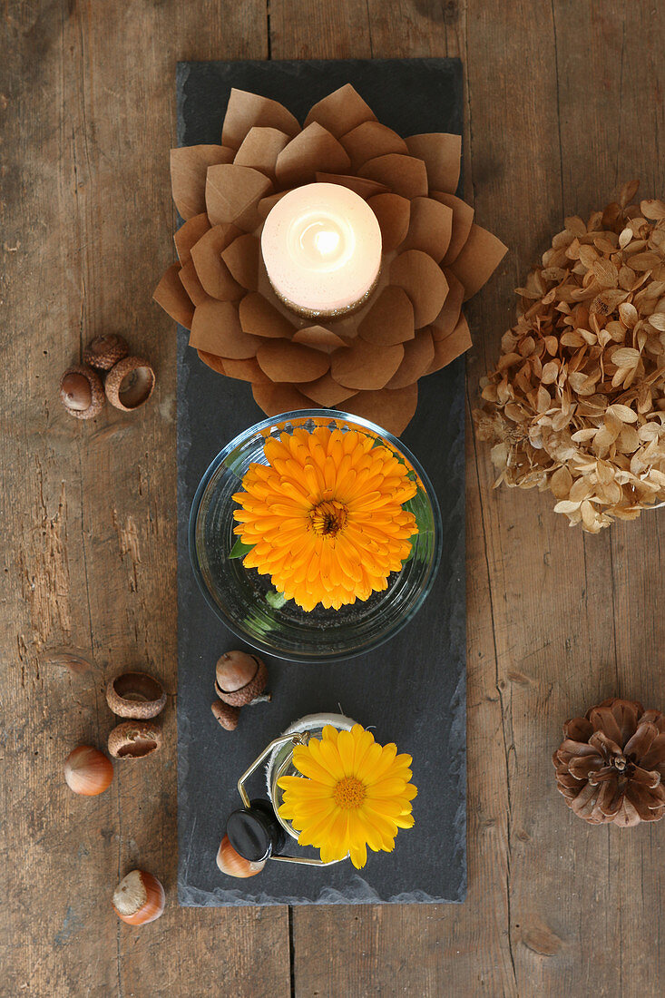 Herbstliches Arrangement aus gelben Astern in Gläsern und Papierblüte als Kerzenhalter